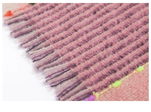 Detail shot of multi-color thick knit scarf with textured fringe and soft pastel yarn