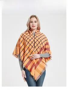 Detailed view of the bright orange plaid scarf with fringe edges and soft knit texture
