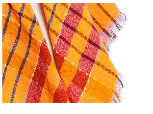Macro detail of orange and red thick checked scarf with boucle yarn texture and fringe