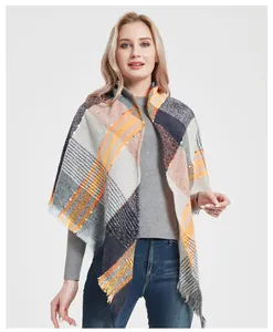 Detail of colorful plaid scarf with fringes in grey, yellow and orange knit fabric