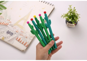 Détail de stylos gel cactus vert avec bouchons fleurs colorés sur un bureau blanc