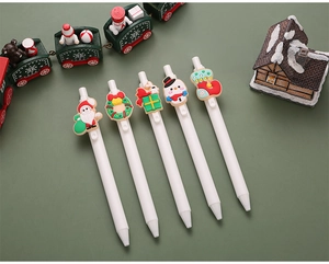 Detailed view of five Christmas gel pens with silicone Santa and snowman charms on green background