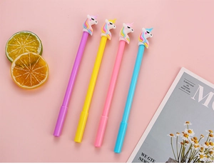 Close-up of four colorful unicorn gel pens with 3D toppers on a pink background