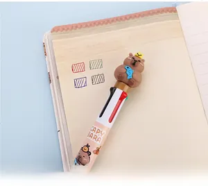 Detail of four-color capybara ballpoint pen with cute 3D topper on a notebook