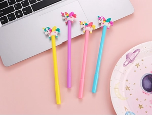 Lot de quatre stylos gel licorne pastel rose, bleu, jaune et violet sur bureau