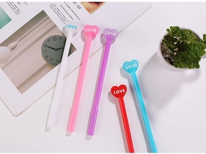 Macro shot of 5 heart-shaped pens with 'LOVE' text on a minimalist workspace table