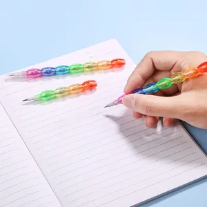 Close-up of hand holding a multi-colored stackable pencil on a notebook for drawing