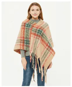 Close-up of beige plaid knit shawl with green and orange patterns and fringe detail