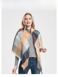 Detail of plaid scarf with fringe trim in gray, orange and blue knit texture