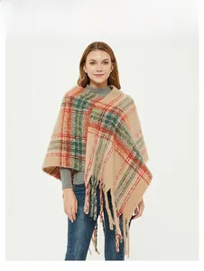 Detail of plaid knit poncho featuring orange and green check pattern with long fringes