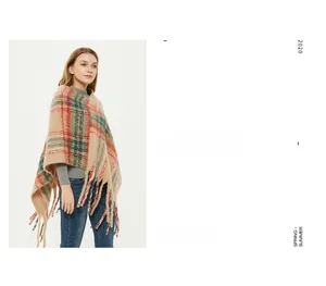 Detail of beige plaid shawl with soft tassels and classic red green grid pattern texture