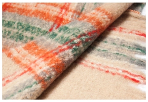 Macro detail of soft plaid mohair poncho fabric with orange and green checkered patterns
