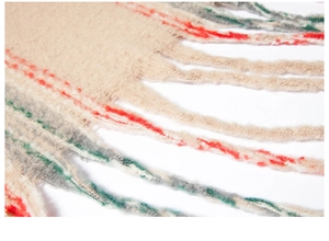 Close-up of knit plaid poncho showing soft faux mohair texture and fringe tassel detail