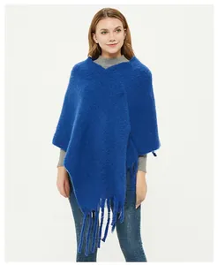Close-up of royal blue knitted poncho featuring thick textured fabric and fringe tassels