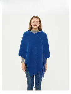 Detailed view of the blue mohair knitted poncho showing asymmetric hem and long tassels