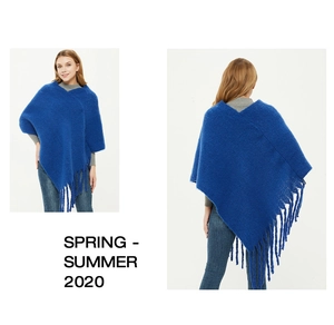 Detail of royal blue knit poncho with long fringe hem and fluffy mohair texture