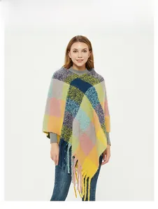 Detail of colorful plaid poncho featuring chunky fringe tassels and asymmetric V-hem design