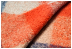 Macro detail of thick plaid shawl showing soft brushed texture and vibrant color block weave