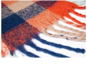 Close-up of thick checkered knit fabric with long tassels in orange and navy blue