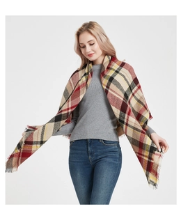 Detailed view of large plaid scarf with fringe edge in red and beige check patterns