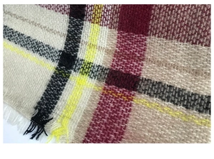 Detail of soft cashmere-like fabric with vintage plaid pattern and fringe edges