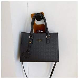 Detail of black quilted leather handbag with gold lettering and heart pendant