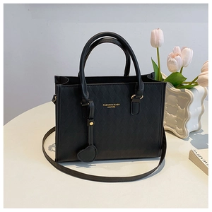 Close-up of black quilted leather handbag with gold lettering and adjustable shoulder strap