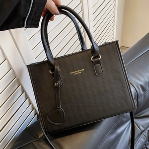 Quilted black handbag with heart charm and shoulder strap shown in a handheld view