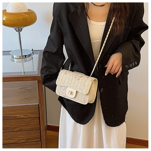 Close-up of beige woven saddle bag with gold metal clasp and chain shoulder strap