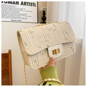 Detail of cream woven bag featuring green floral embroidery and golden metal twist lock