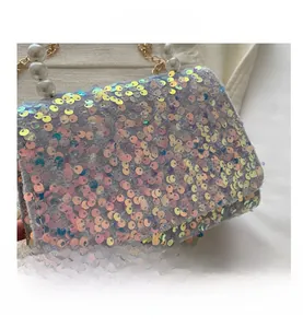 Detail of colorful sequin evening bag with large pearl handle and gold metal chain
