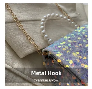 Detail view of iridescent sequins and gold hardware hook with white pearl handle