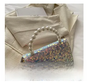 Detail of sequin handbag with pearl handle and golden chain on beige fabric