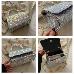 Detail of sequin handbag featuring pearl handle and detachable gold chain strap