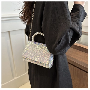 Close-up of sparkling sequin crossbody bag with elegant pearl handle and gold chain strap