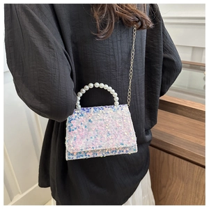 Detail of sequin flap crossbody bag with white pearl handle and gold chain on model
