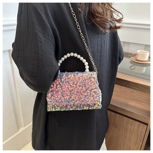 Detail of iridescent sequin handbag featuring a faux pearl handle and gold chain strap