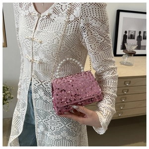 Close-up of pink sequin square handbag with pearl handle and golden chain strap