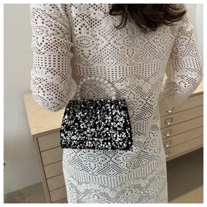 Close-up of elegant sequined handbag with faux pearl handle and gold chain strap