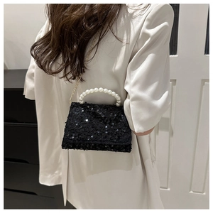 Detail of black sequined crossbody bag with pearl handle and golden chain strap
