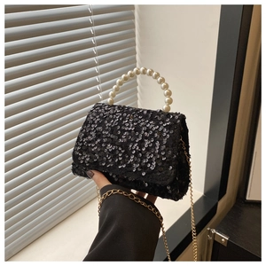 Close-up of black sequined handbag featuring a pearl handle and gold chain strap