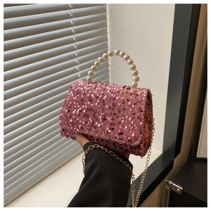 Detailed macro view of pink sequined handbag with faux pearl handle and gold chain strap