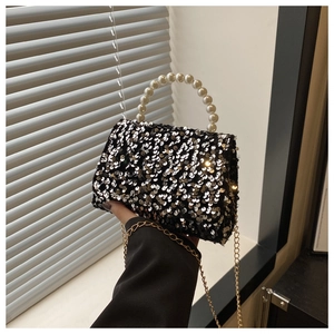 Close-up of sparkling black sequins and elegant pearl handle on a small luxury handbag