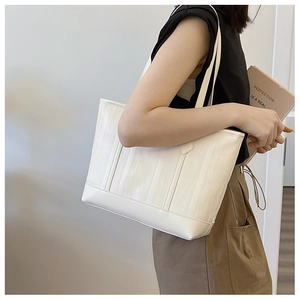Détail du sac cabas blanc avec texture ondulée verticale et fines bandoulières
