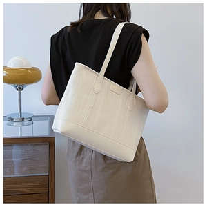 Détail d'un grand sac cabas blanc cassé texturé avec rayures verticales et métal doré