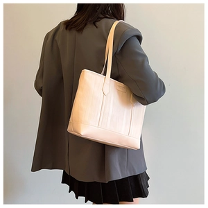 Gros plan d'un sac cabas beige avec texture gaufrée verticale et longues bandoulières
