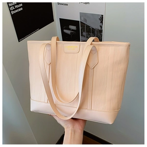 Détail du sac cabas beige clair avec motif gaufré ondulé et logo doré imprimé