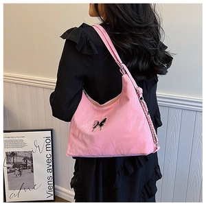 Detailed view of pink shoulder bag with butterfly charm and metal chain strap decoration