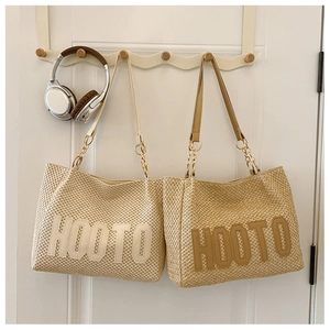 Detail of straw tote bags with leather chain handles and HOOTO lettering design