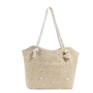 Large beige woven straw tote bag with floral embroidery and white cotton rope handles